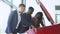 Professional car salesman is telling interested buyers african american couple about luxurious car in motor show
