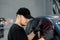 Professional car service worker wearing black cap and t-shirt, tinting a car window with tinted foil or film in auto