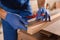 Professional carpenter making mark on wooden bar in workshop, closeup