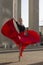 Professional Caucasian Ballet Dancer in Red Dress Posing in Red Skirt While in Dance Pose With Lifted Dress Against Pillars