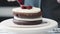 Professional chef is cooking cake. Close up of chef puts Cherry jam on white cream