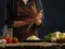 A professional chef grates cheese on a dark blue background. Vegetables, eggs, greens lie on a wooden table. Cooking salad,