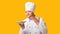 Professional Chef Holding Empty Plate Smelling Invisible Dish, Yellow Background