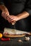 Professional chef prepares fresh fish bighead carp sprinkling pepper. Preparing to cook fish food. Working environment in the