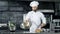 Professional chef throwing food in pan with burning flame at kitchen