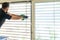 Professional cleaner deep cleaning window blinds in an apartment with a green microfiber cloth