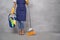 Professional Cleaning Service. Cropped shot of woman in uniform and yellow rubber gloves holding broom and bucket with