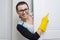 Professional cleaning service. Woman housemaid in yellow rubber gloves pointing with a finger to the white door is the place of co