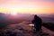 Professional on cliff. Nature photographer takes photos with mirror camera on peak of rock.