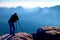 Professional on cliff. Nature photographer takes photos with mirror camera on peak of rock. Dreamy blue fogy landscape,