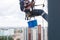 Professional climber rope access worker painting, repairing and cleaning windows on the facade of residential skyscraper high rise