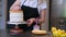 Professional confectioner in black apron connecting cake layers smeared with cream