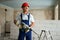 Professional construction worker in uniform standing with rotary hammer drill. Portrait of contractor in hardhat and