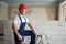 Professional construction worker in uniform standing with spatula on step ladder. Portrait of contractor in hardhat