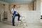 Professional construction worker in uniform standing with spatula on step ladder. Portrait of contractor in hardhat