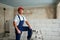 Professional construction worker in uniform standing with spatula on step ladder. Portrait of contractor in hardhat