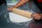 A professional cooker hands rolling out pastry to make delicious pizza on steel  table at restaurant .