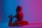 Professional cool young woman in fashionable sportswear doing fitness in a room with multicolored neon color. Attractive girl yoga