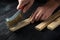 Professional craftsman cleans the wood plank with an abrasive tool. Builder hands close up. Renovation or construction idea