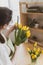 Professional creation of flower arrangement. Woman florist in an apron puts beautiful yellow flowers in a transparent