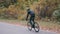 Professional cyclist in black sportswear and helmet riding on road bike in autumn city park. Man intensive training on road bicycl