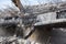 Professional demolition of reinforced concrete structures using industrial hydraulic hammer. Rods of metal fittings. Wreckage and