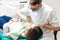 Professional dentist doing teeth checkup on female patient dental surgery