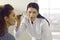 Professional dermatologist holding magnifying glass and examining skin on woman's face