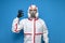 Professional disinfector man in protective suit shows okay sign on blue  background, disinfection service worker