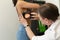 A professional doctor dermatologist advises young patient. Examines a mole on the arm with a dermatoscope