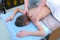 Professional doctor masseur making massage to teen boy on back spine in clinic.