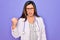Professional doctor woman wearing stethoscope and medical coat over purple background angry and mad raising fist frustrated and