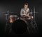 Professional drummer playing on drum set on stage on the black background