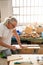 Professional elderly man carpenter artist working on wood using carpentry tools in the workshop