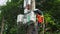 A professional electrician performs installation work on a pole. An electrician in professional equipment, working in dangerous co