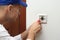 Professional electrician with screwdriver repairing light switch indoors, closeup