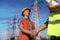 Professional electricians shaking hands near high voltage tower