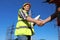 Professional electricians shaking hands near high voltage tower