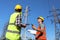 Professional electricians in uniforms near high voltage towers