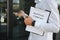 Professional estate seller with clipboard writing documents outside in front of rented house with advertising area