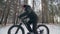 Professional extreme sportsman biker riding a fat bike in outdoors. Cyclist ride in the winter snow forest. Man does