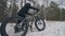 Professional extreme sportsman biker walk with fat bike in outdoors. Cyclist walking in the winter snow forest. Man go