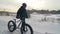 Professional extreme sportsman biker walk with fat bike in outdoors. Cyclist walking in the winter snow forest. Man go