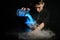 Professional female barman pours illuminated smoky cocktail from mixing bowl into martini glass.