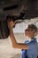 Professional female mechanic holding tools fixing undercarriage of vehicle, tire