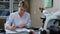 Professional female research assistant in white coat sitting at the table with microscope and calculator in front of her