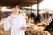 Professional female vet standing near calves barn in livestock farm