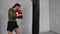 Professional fighter is training in a gym practicing some kicks and punches with punching bag.