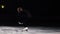 The professional figure skater in a black suit performs the power of the tops on ice in ice skates in a slow-motion shot