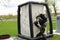 A professional firefighter in a black special fireproof suit prepares to assemble a white oxygen tent to rescue people at a chemic